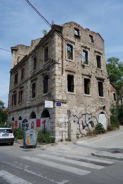 Mostar: Discovering the scars of the war that rocked Bosnia. The bombed out buildings that remain, Bosnia and Herzegovina, Bombed out buildings, sniper towner, exploring the sniper tower, how to get in, is it safe, mountains, cross, view from sniper tower, bullet holes, yugoslavia, balkan war, siege, fighting, croats, serbs, bosnians, muslims, front line, history