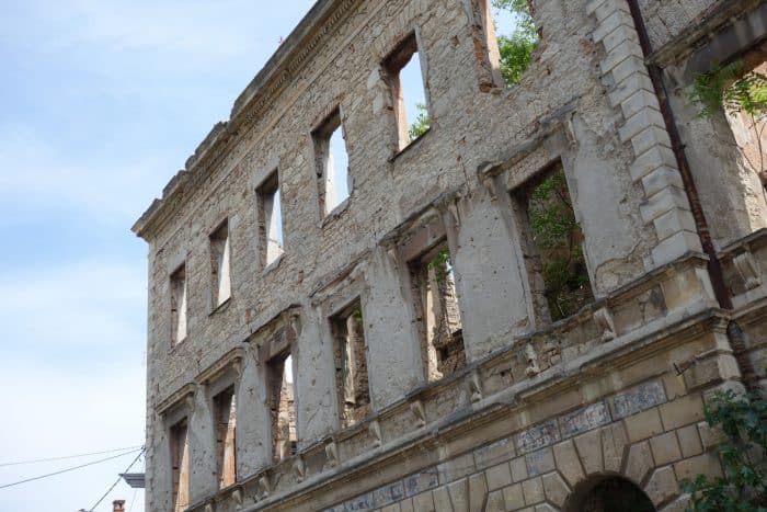 Mostar: Discovering the scars of the war that rocked Bosnia. The bombed out buildings that remain, Bosnia and Herzegovina, Bombed out buildings, sniper towner, exploring the sniper tower, how to get in, is it safe, mountains, cross, view from sniper tower, bullet holes, yugoslavia, balkan war, siege, fighting, croats, serbs, bosnians, muslims, front line, history