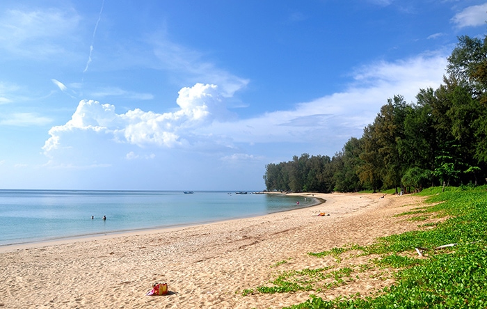 looking out over a golden sandy beach, blue sea and clear sky with some massive clouds in the distance. 