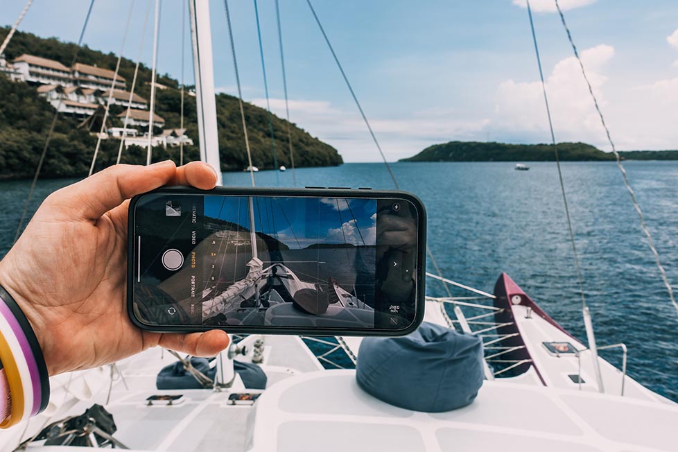 Someone holding a phone with the camera app open whilst on a catamaran in the sea Thailand backpacking packing list guide.