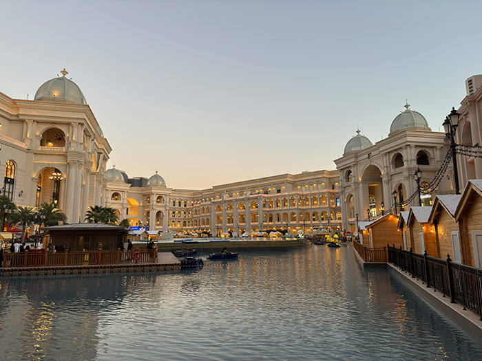 A large lake with boats on it and ornate architecture inside an open air section of a mall in Doha, Qatar