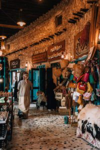 A man walking through the souk with shops and stalls around him and signs in Arabic in Doha, Qatar