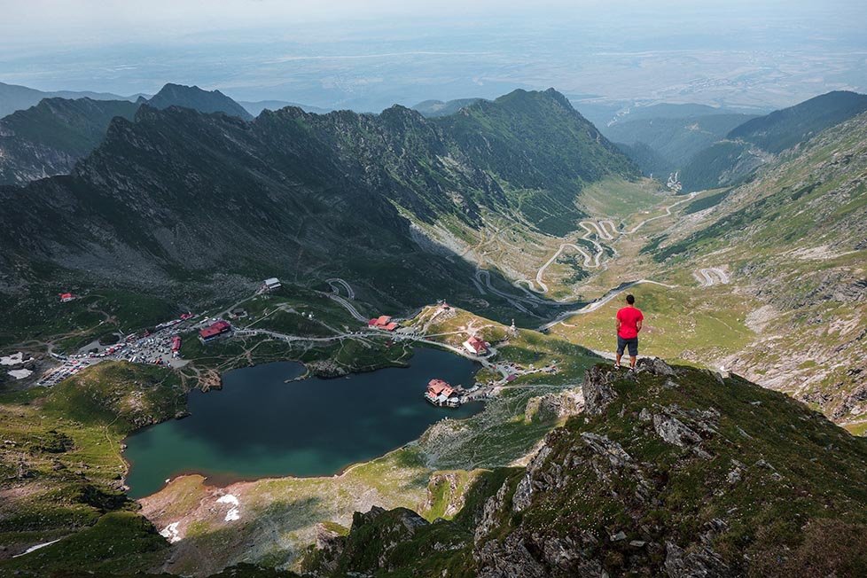 A person standing looking over a view point in the Carpathian mountains in Romania.