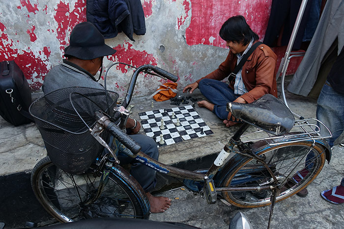 Two men next to a crumbling wall are playing chess on the street in Yogyakarta, Indonesia