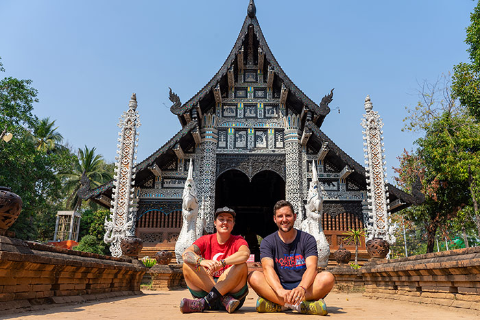 Nic and Shorty sitting down with their legs crossed outside a temple in Chiang Mai, Thailand