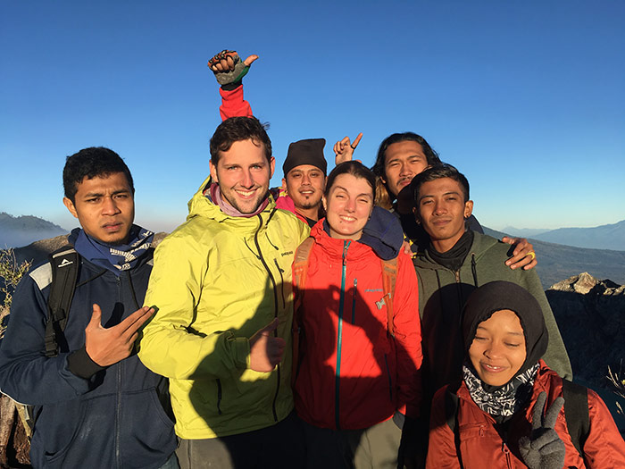 Nic and shorty standing on top of mt Ijen volcano in Indonesia with a group of Indonesia people after summiting at sunrise