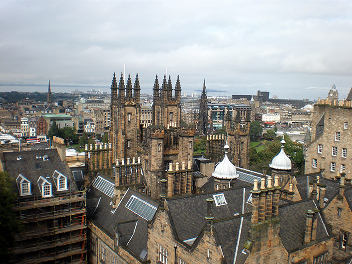 An image looking out over the stone buildings of Edinburgh, Scotland with the port in the distance
