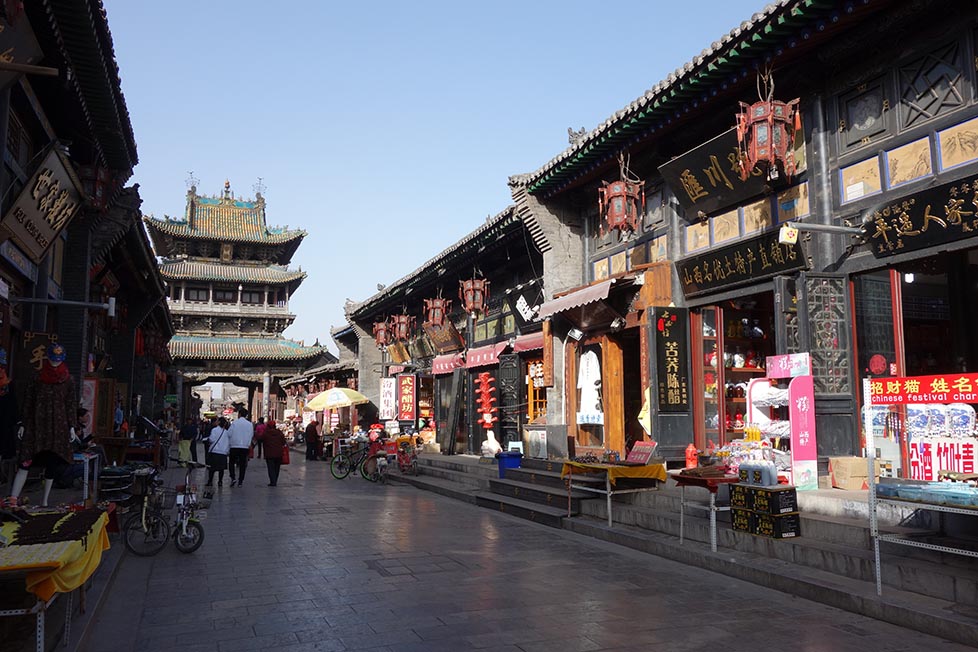 Looking down the main street in Pingyao at the traditional shophouses and decorative main gate