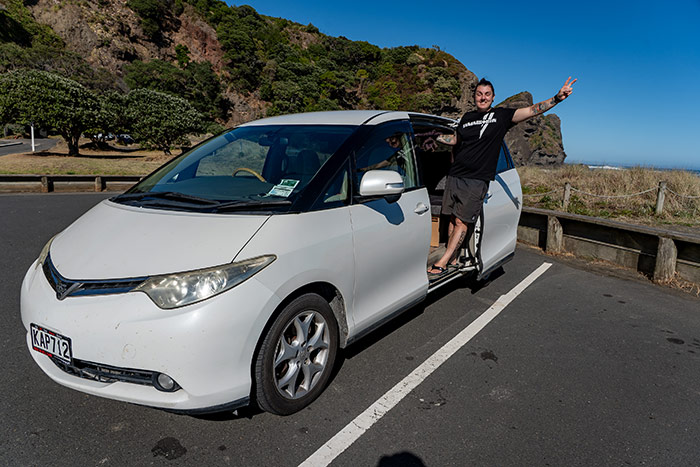 Nic hanging out of a campervan at Piha beach in New Zealand