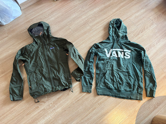 A waterproof jacket and a hoodie laid out on the floor below, and across are the waterproof jacket and hoodie packed down into their packing sacks.