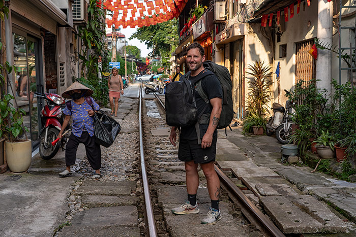 Shorty stood on train street in Hanoi carrying his backpacks.